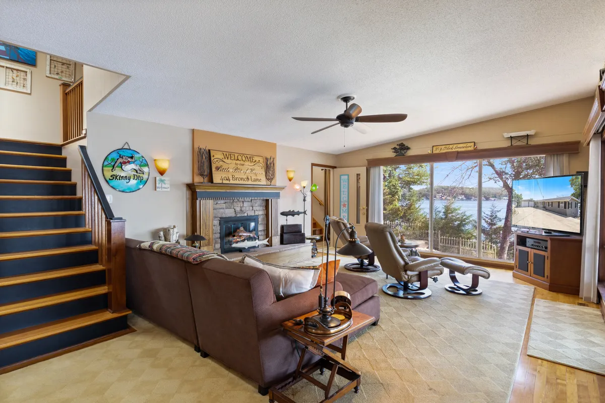 A cozy living space featuring a comfortable seating area arranged around a fireplace, with expansive windows offering breathtaking views of the lake. The room exudes warmth and togetherness, perfect for relaxing, entertaining, or simply enjoying the scenery.