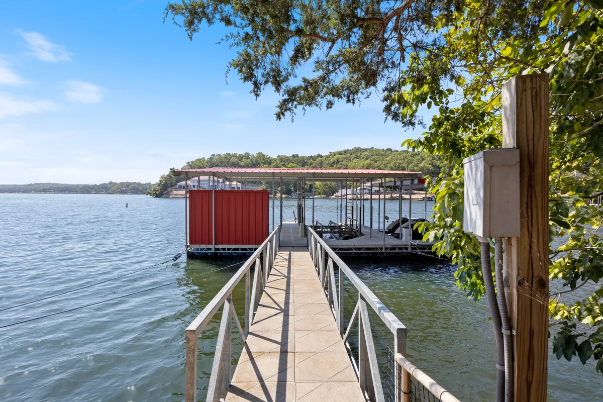This exterior photo captures the private dock and boathouse set against serene waters, surrounded by lush greenery. The dock extends out into the lake, inviting families to swim, fish, or launch water activities directly from their retreat. The calm water and scenic backdrop highlight opportunities for both relaxation and fun.