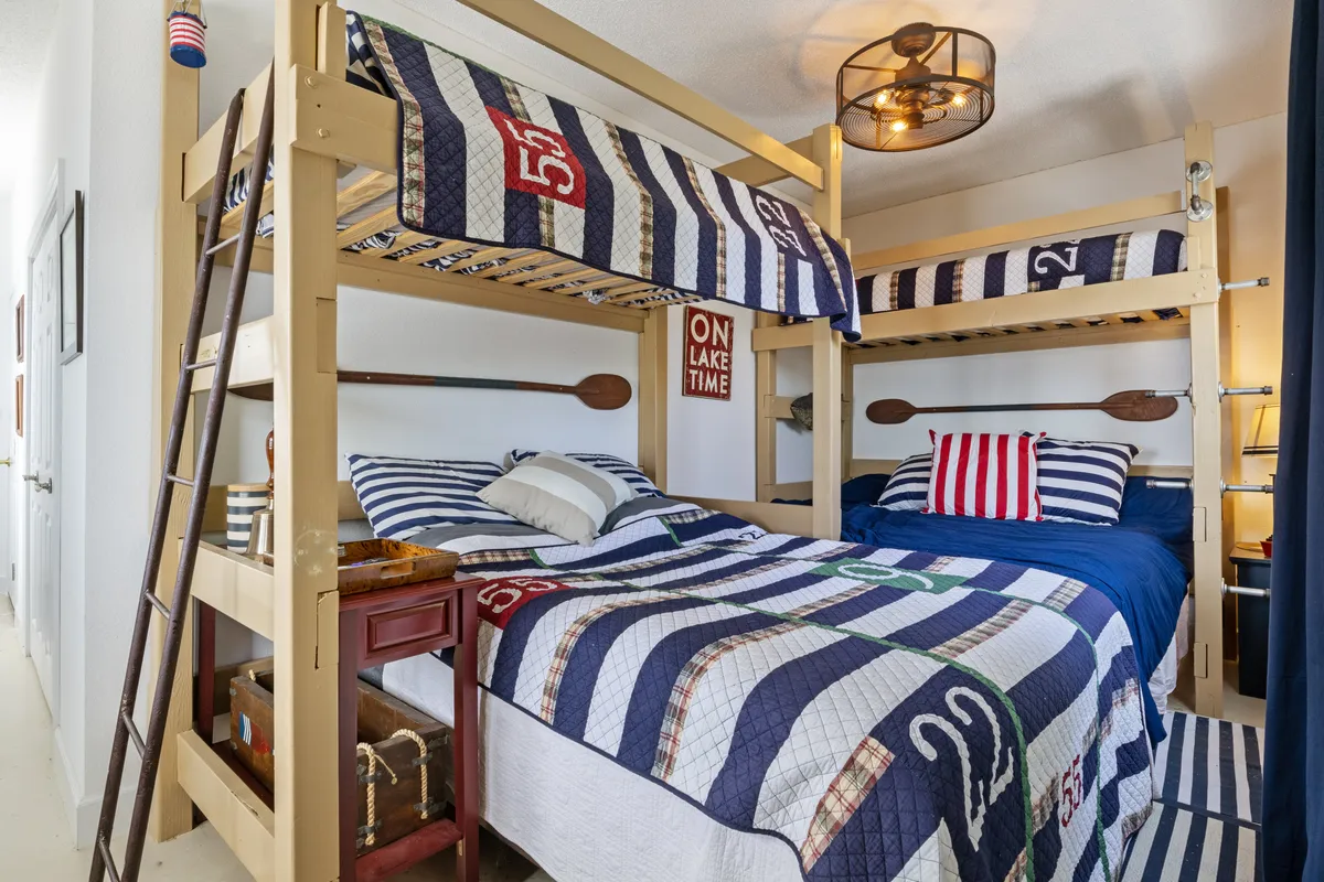 A bright and playful bunk bedroom featuring charming striped bedding, decorative oars on the wall, and a unique light fixture. The room is designed with children and families in mind, inviting fun, comfort, and togetherness.