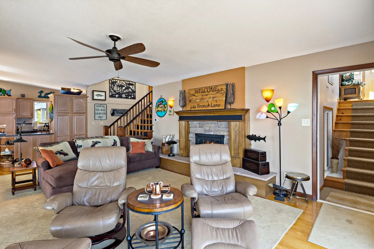 A cozy interior vignette showcasing plush recliners, a warm fireplace, and inviting decor. The scene captures an atmosphere ideal for both relaxation and social gatherings, with thoughtful touches like decorative wall signs and a colorful lamp.