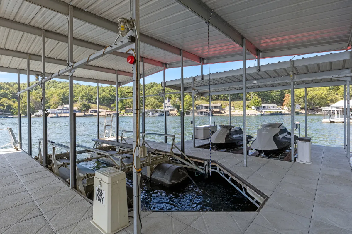 A view focused on the dock area, with boat lifts resting above the water's surface and rich greenery enveloping the shoreline. The scene is leisurely and inviting, emphasizing opportunities for boating and easy gear storage.
