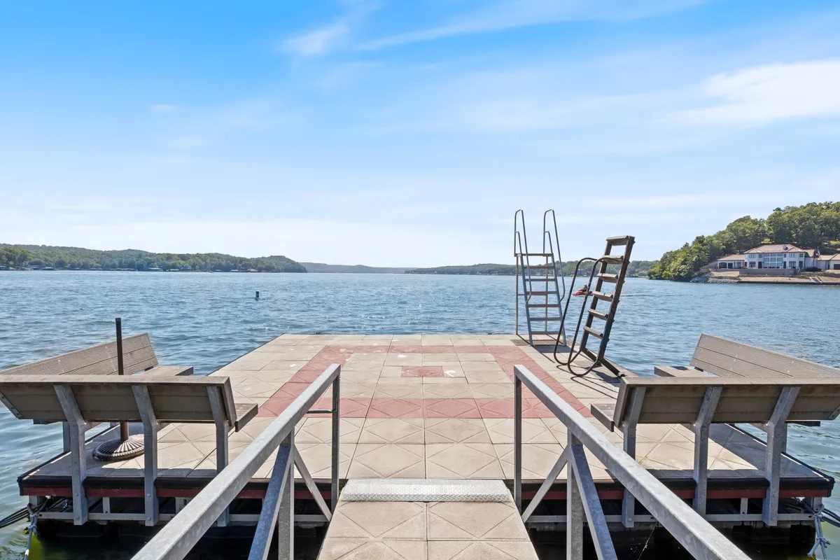 A peaceful view of the dock featuring a swim ladder and benches, surrounded by calm lake water. The setting is ideal for jumping in for a swim, casting a fishing line, or relaxing to enjoy the view, with golden hour light suggesting the end of an active lakeside day.
