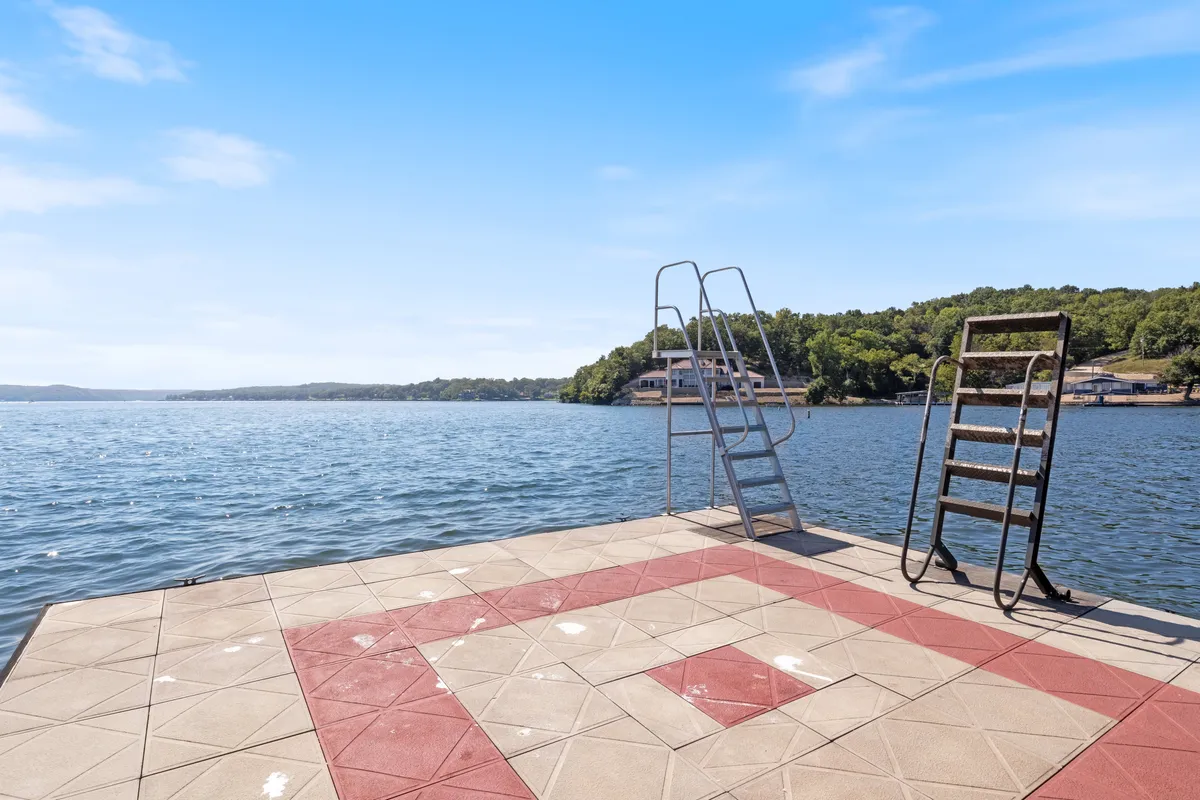 A sunlit shot of the swim platform and dive pier highlights a dedicated area for swimming, sunbathing, or fishing. The lake and surrounding greenery create a sense of adventure and connection to nature, perfect for family play and relaxation.