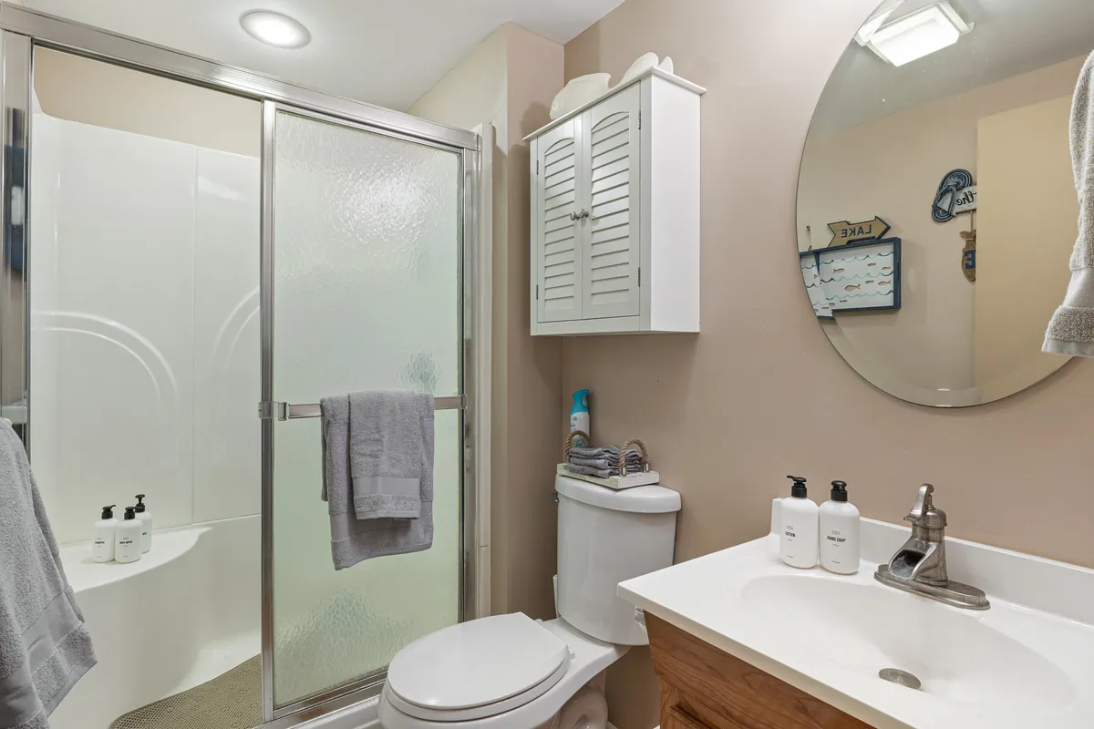 A well-appointed full bathroom featuring a walk-in shower, a modern vanity with a sink and mirror, and a storage cabinet. The ambiance is peaceful and inviting, perfect for morning or evening routines.