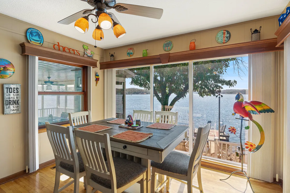 A sun-drenched dining area with a welcoming table surrounded by chairs, large windows revealing picturesque views of the shimmering lake, and vibrant decor that adds warmth. The space is designed for family meals and friendly gatherings, with natural light flooding in to create an inviting atmosphere.